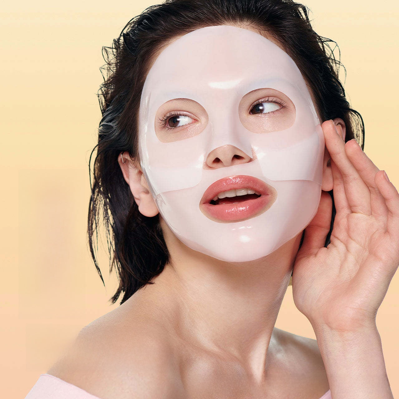 Woman wearing a white face mask against a beige background